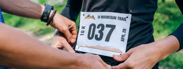 Manos colocando el dorsal de una carrera de montaña sobre la camiseta